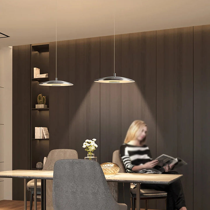 Scène de vie montrant une suspension design moderne éclairant un espace de lecture élégant.