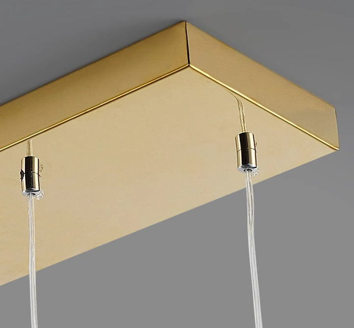 Gros plan sur le support de plafond rectangulaire doré d'un luminaire suspendu design.