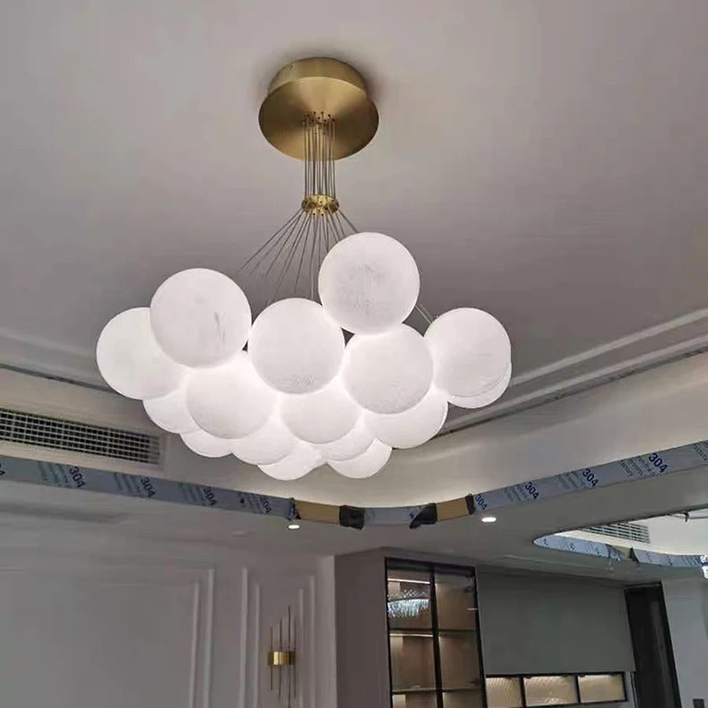 Suspension à 19 globes en verre opalin blanc installée dans un salon moderne avec rosace dorée au plafond