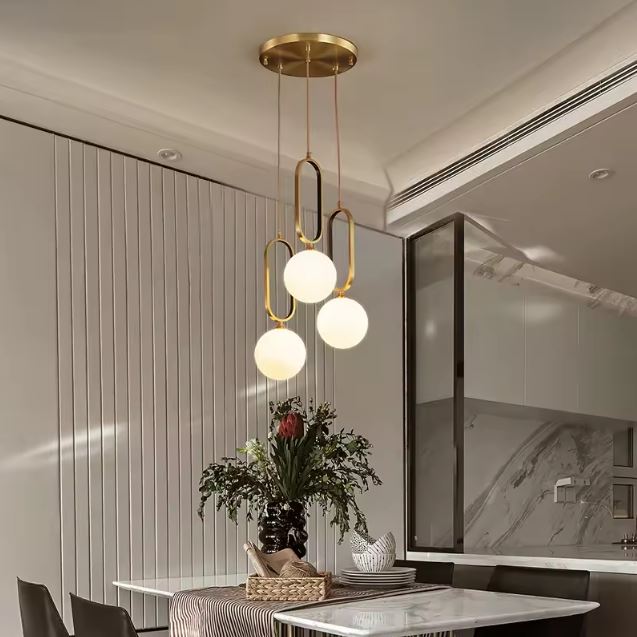 Suspension 3 globes en laiton et verre blanc, luminaire chic aux accents contemporains pour une salle à manger raffinée.