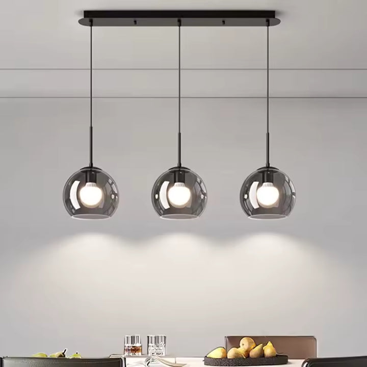 Trois globes en verre fumé alignés sur une suspension noire moderne aux ampoules apparentes