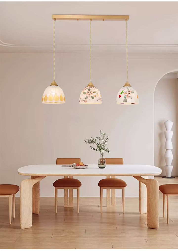 Suspension 3 lampes en verre façonné aux décors marins, associée à une salle à manger naturelle et épurée
