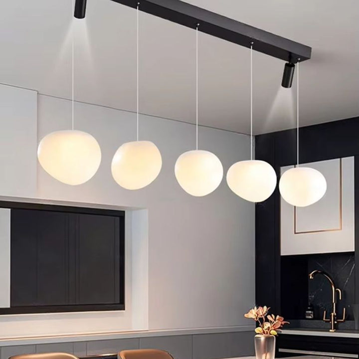Alignement élégant de cinq globes opalins sur une suspension linéaire noire au style moderne et minimaliste