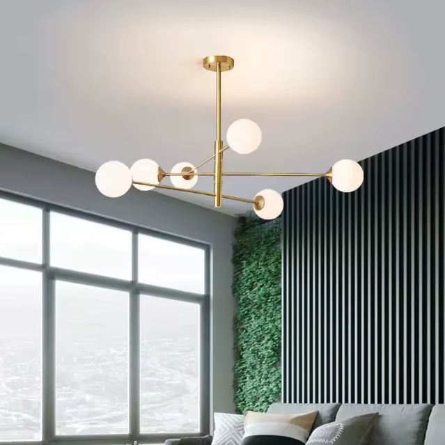 Suspension 6 globes en verre opaline et métal doré installée dans un salon moderne et lumineux, idéale pour une décoration élégante.