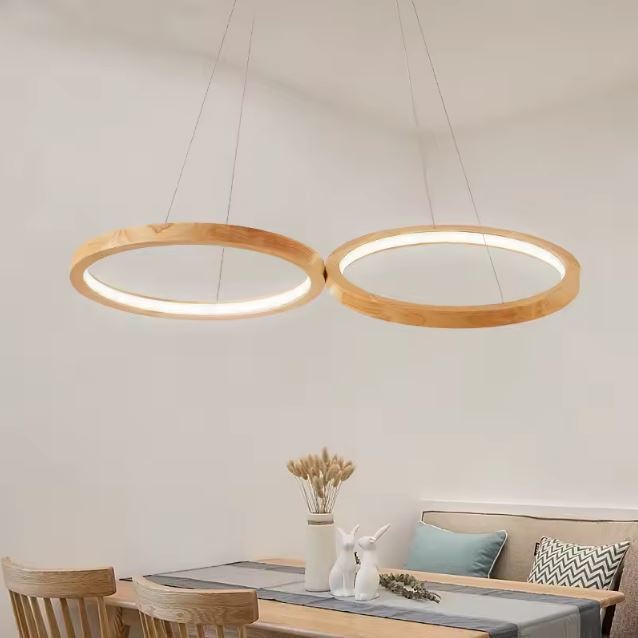 Suspension anneau bois double installée dans une salle à manger bohème, avec mobilier clair et ambiance naturelle apaisante.