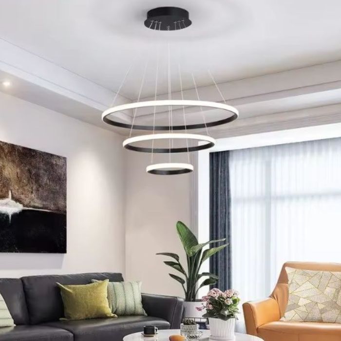 Suspension anneau LED noire au design italien, mise en valeur avec une plante décorative pour un salon élégant.