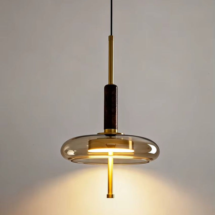 Suspension design à anneau de verre, tige dorée et bois foncé diffusant une lumière chaude contemporaine