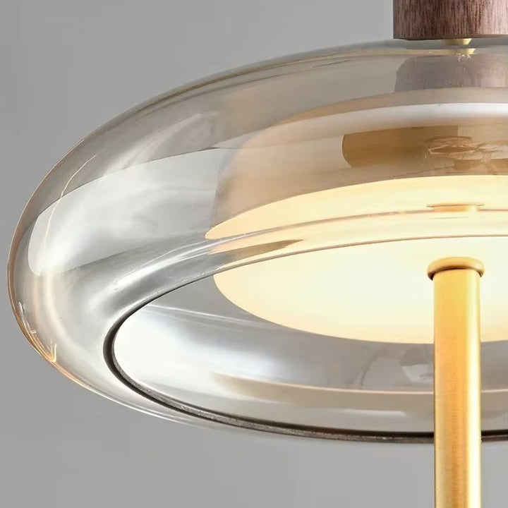 Détail de l’anneau en verre de la suspension à tige dorée, diffusant une lumière douce au design épuré