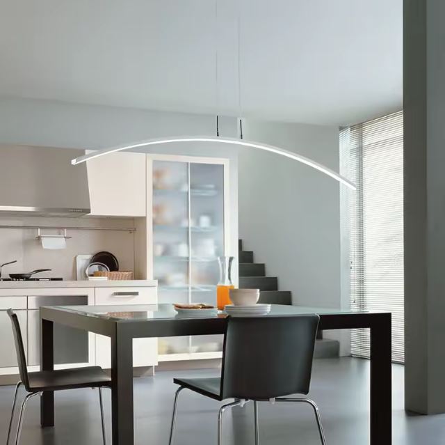 Suspension arc LED moderne éclairant une cuisine contemporaine avec table noire, pour un design élégant et fonctionnel.