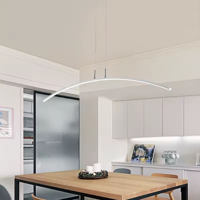 Suspension arc LED minimaliste éclairant une salle à manger avec table en bois et cuisine blanche moderne.