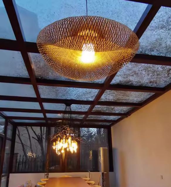 Suspension en bambou tressé au style ethnique contemporain, luminaire chaleureux au-dessus d’une grande table élégante.
