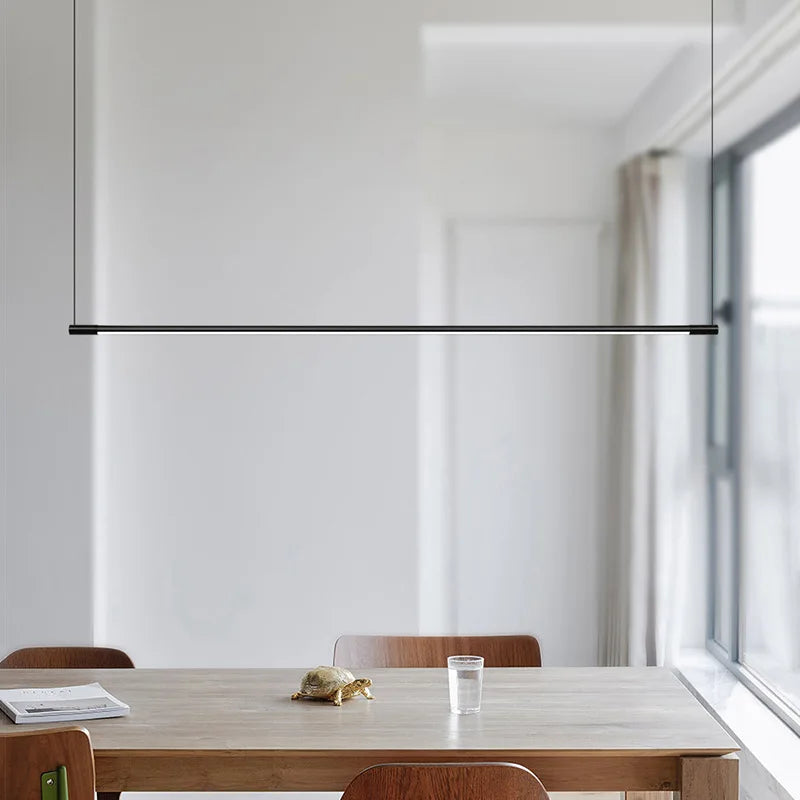 Éclairage intérieur minimaliste assuré par une longue suspension fine LED noir mat.