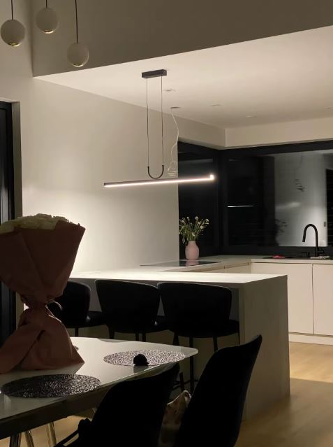 Suspension barre LED noire au style minimaliste contemporain, luminaire linéaire élégant au-dessus d’un îlot de cuisine moderne.
