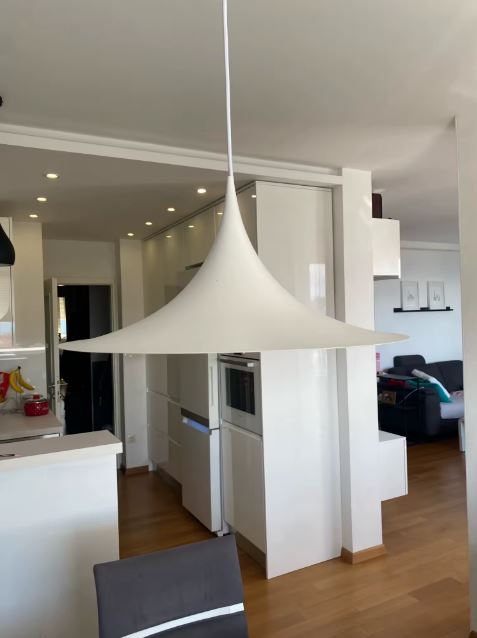 Grande suspension blanche aux courbes tendues dans une cuisine ouverte, entre japandi, modernisme et sobriété scandinave.