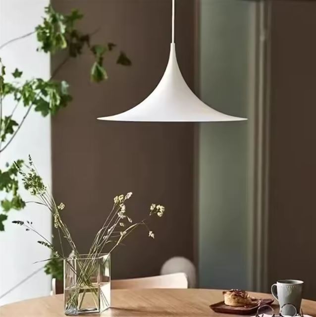 Suspension blanche aux lignes élancées au-dessus d’une table en bois, esprit japandi et scandinave apaisant.