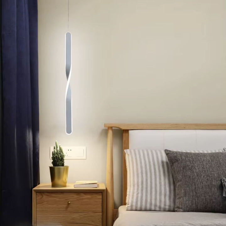 Au bord du lit, cette suspension blanche torsadée apporte une lumière douce à une chambre d’inspiration scandinave