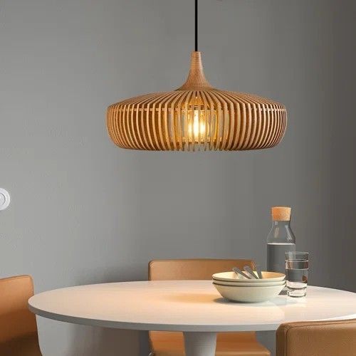 Suspension ronde en bois ajouré éclairant un coin repas moderne et minimaliste.