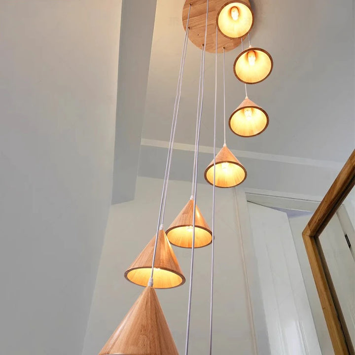 Détail d'une suspension scandinave en bois avec cônes LED allumés pour une ambiance chaleureuse et feutrée.