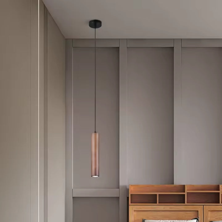 Suspension cylindrique en bois foncé dans une chambre épurée au style japandi et minimaliste