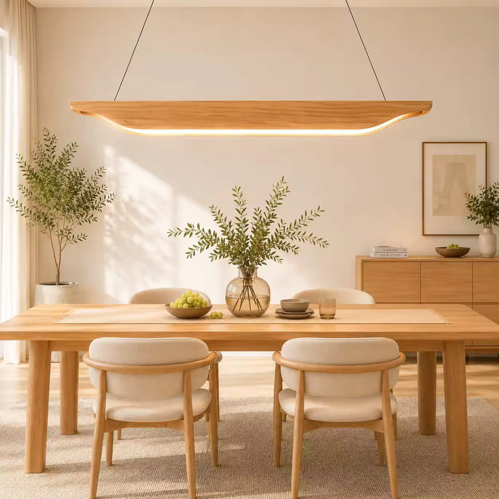 Élégante suspension en bois clair aux extrémités incurvées, éclairant une grande table dans un intérieur scandinave épuré.