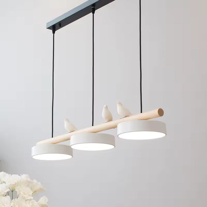 Avec ses trois disques blancs et ses oiseaux posés sur le bois clair, ce lustre évoque un style nordique doux