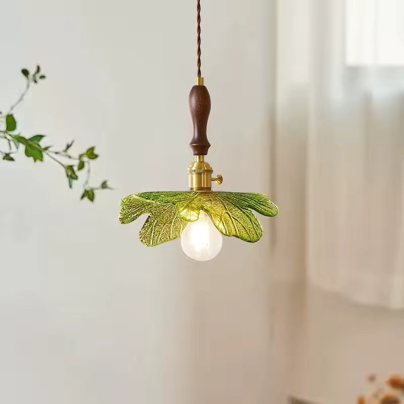 Feuillage en verre vert sculpté autour d’une suspension en bois de noyer au charme botanique et naturel