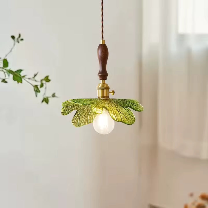 Feuillage en verre vert sculpté autour d’une suspension en bois de noyer au charme botanique et naturel