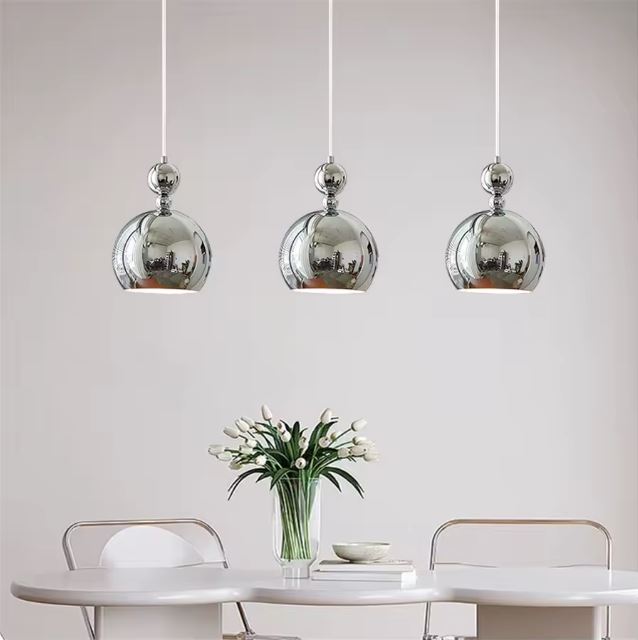 Ensemble de trois suspensions boules argentées élégantes, parfaites pour illuminer une salle à manger moderne.