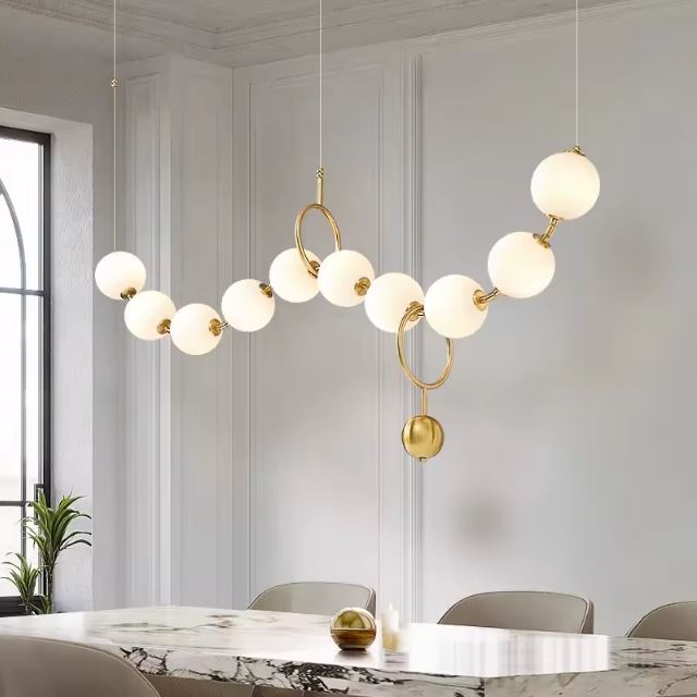 Suspension boule blanche et doré dans une salle à manger élégante avec table en marbre et décor moderne.