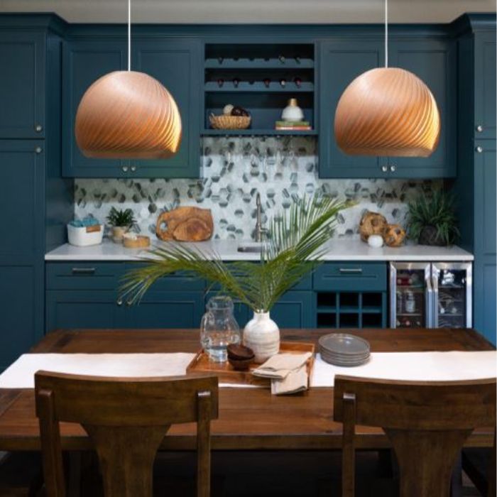 Suspension boule en bois installée au-dessus d'une table dans une cuisine moderne avec des armoires bleues.