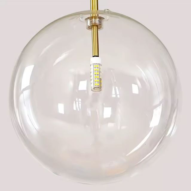 Détail d'une suspension boule en verre transparent avec un éclairage LED intégré dans un design moderne et élégant.