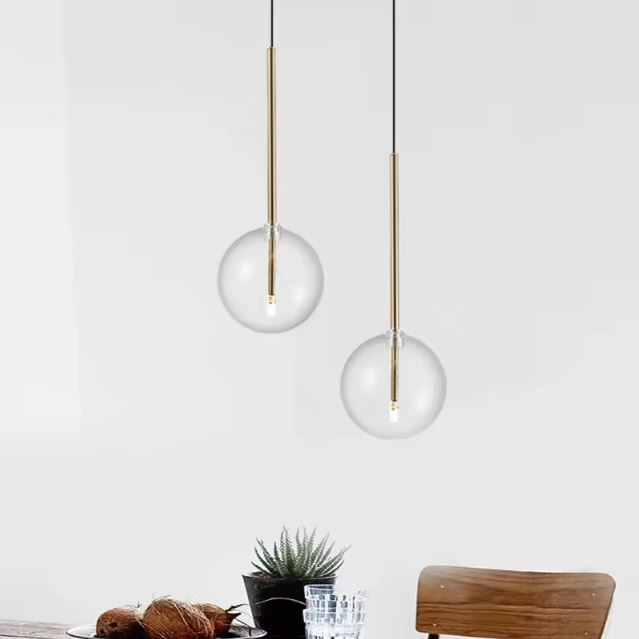 Suspension boule en verre transparent avec support doré, créant une ambiance lumineuse élégante et moderne pour une décoration intérieure raffinée.