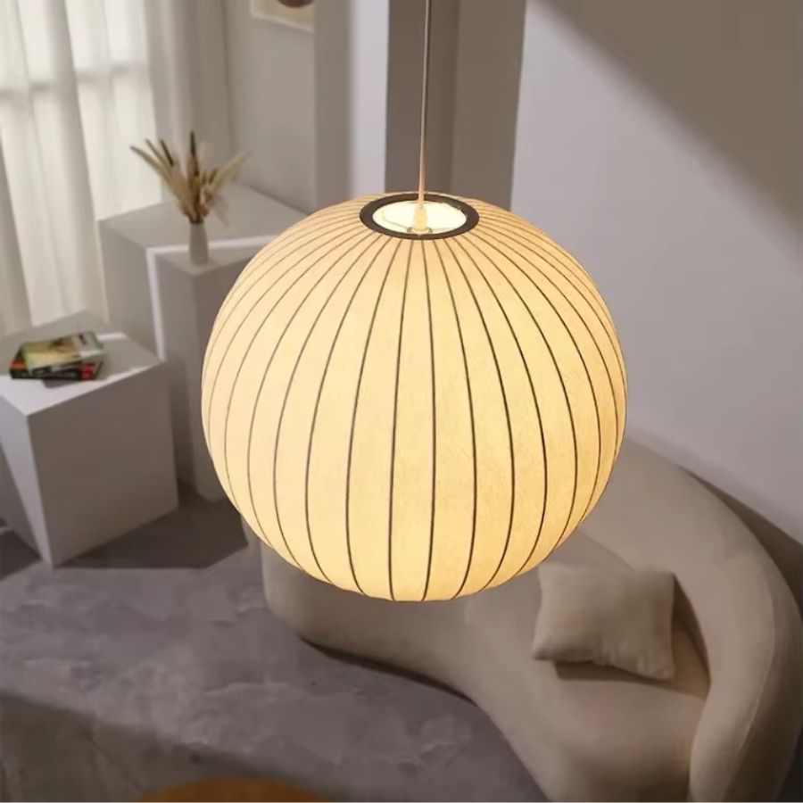 Suspension boule en soie blanche lumineuse au style japandi et organique, créant une ambiance douce dans un salon épuré