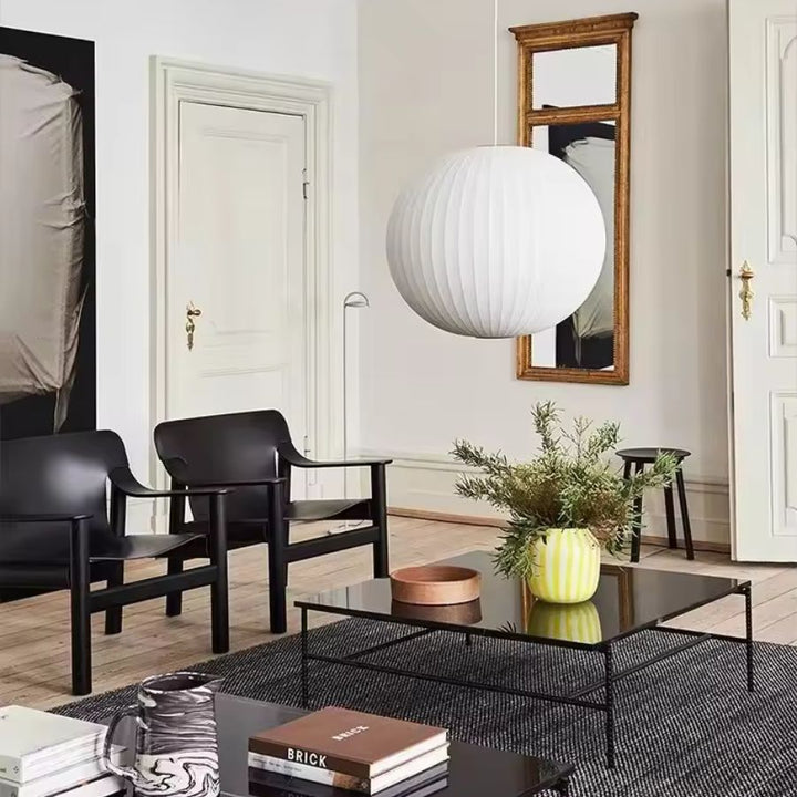 Suspension boule en soie blanche plissée au style moderne et raffiné, installée comme pièce centrale dans un salon élégant