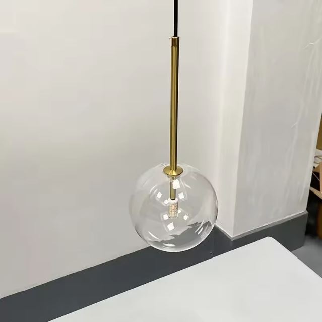 Suspension boule en verre transparent avec design minimaliste et structure dorée, idéale pour une ambiance moderne et épurée dans tout intérieur.