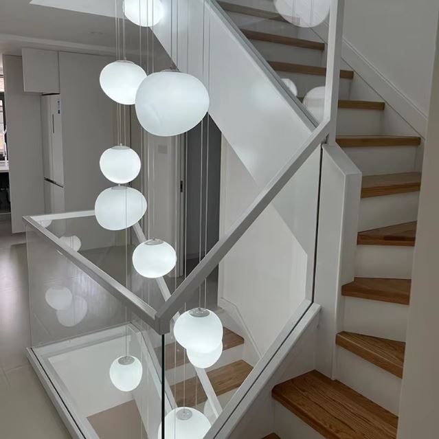 Suspension boules blanches dans une cage d’escalier, luminaire épuré au style contemporain et lumineux.