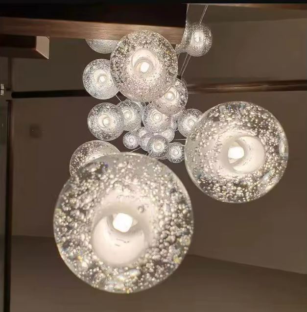 Suspension à boules en verre bullé transparent, luminaire design en cascade aux reflets scintillants et à l’esprit luxe moderne.