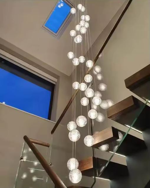 Suspension à boules en cristal en cascade, luminaire raffiné illuminant une cage d’escalier avec une élégance aérienne.