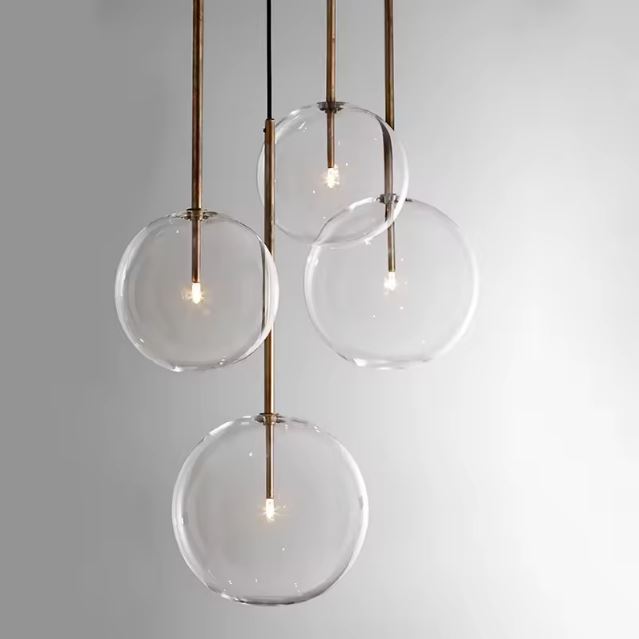 Suspension avec quatre boules en verre transparent suspendues, éclairage moderne et élégant avec structure dorée.