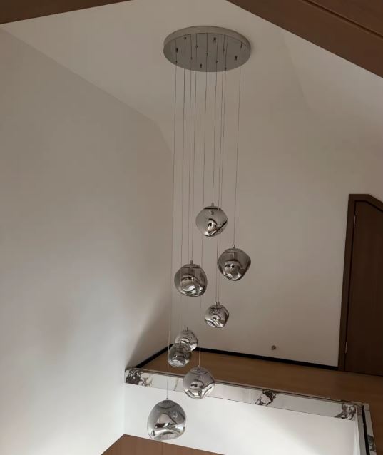 Suspension à boules miroir en cascade, luminaire design architectural sublimant un plafond haut avec élégance moderne.