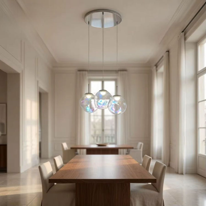 Suspension à trois sphères en verre irisé dans une salle à manger lumineuse au style élégant et contemporain