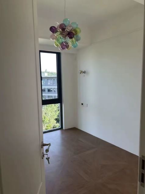 Bouquet de globes en verre translucide coloré suspendu dans une chambre épurée, avec une touche contemporaine et ludique.