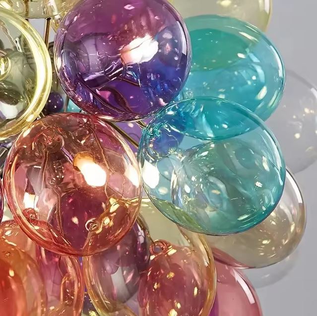 Détail des globes en verre coloré translucide d'une suspension artistique, entre reflets irisés et esthétique pop.
