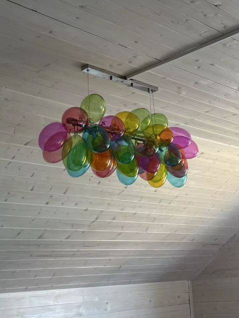 Suspension linéaire en globes de verre coloré translucide, formant une composition aérienne au style artistique et organique.