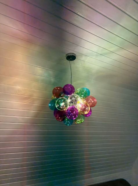 Suspension en globes de verre coloré projetant des reflets multicolores, avec une esthétique pop et contemporaine.