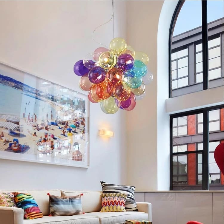 Suspension design en verre translucide multicolore installée près d'une grande baie vitrée lumineuse.