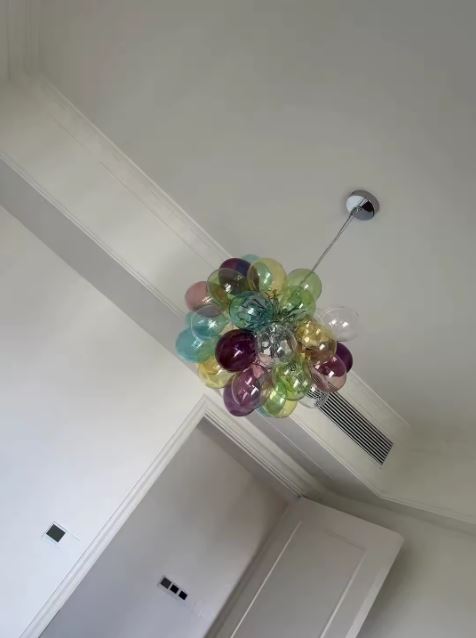 Vue de dessous d'une suspension en globes de verre coloré, formant un bouquet aérien au design organique et artistique.