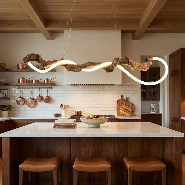 Au-dessus d'un îlot de cuisine en bois, suspension sculpturale effet branche d'arbre enlacée d'un néon LED blanc.