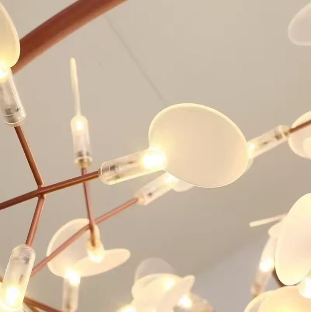 Gros plan sur une suspension branche au style organique, révélant ses diffuseurs lumineux délicats et son design contemporain raffiné.