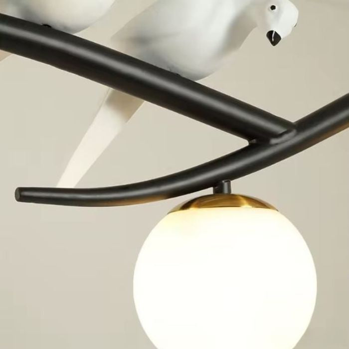 Gros plan sur une suspension branche noire avec oiseau décoratif et globe opalin au style minimaliste et poétique